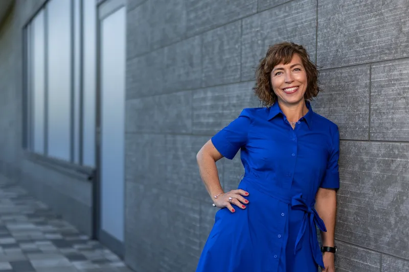 Frida, Manager Business Navigation HQ at Axis, standing in front of the Grenden building, smiling.
