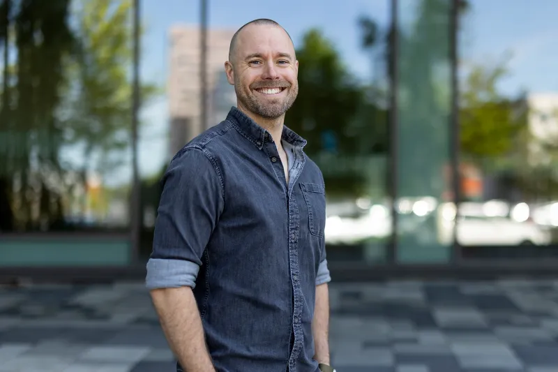Jonathan, Health and Safety Specialist at Axis, smiling in front of the Grenden building at Axis HQ.