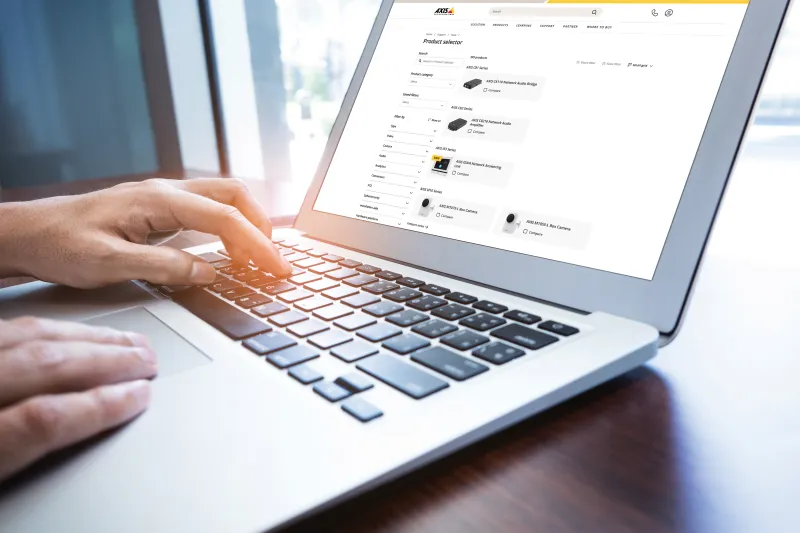 A hand navigation on a laptop displaying Axis product selection.