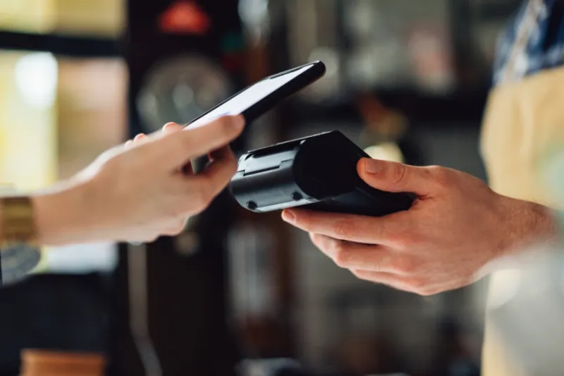 A hand holding a phone while scanning the sensor to a card reader.