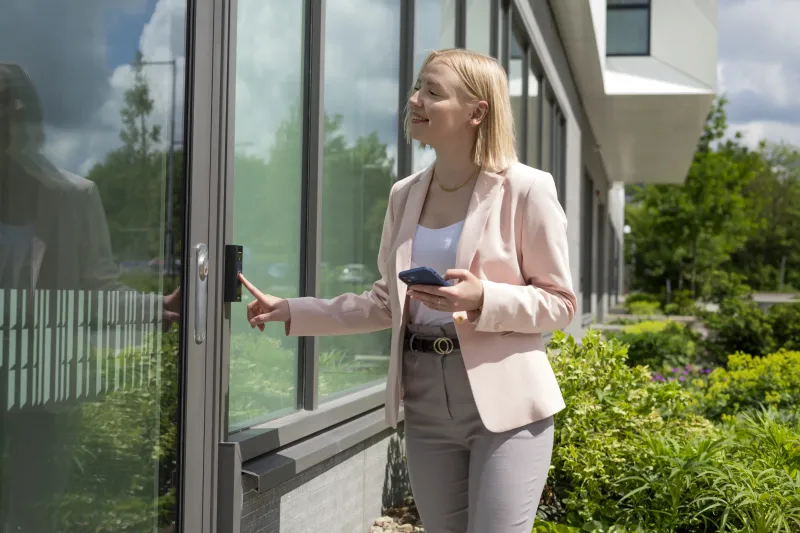 Woman pushing a button outside an exterior door for access.