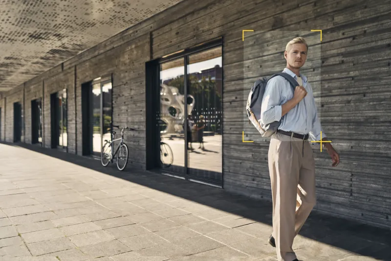 Man walking outside a big building with object detection frame around him.