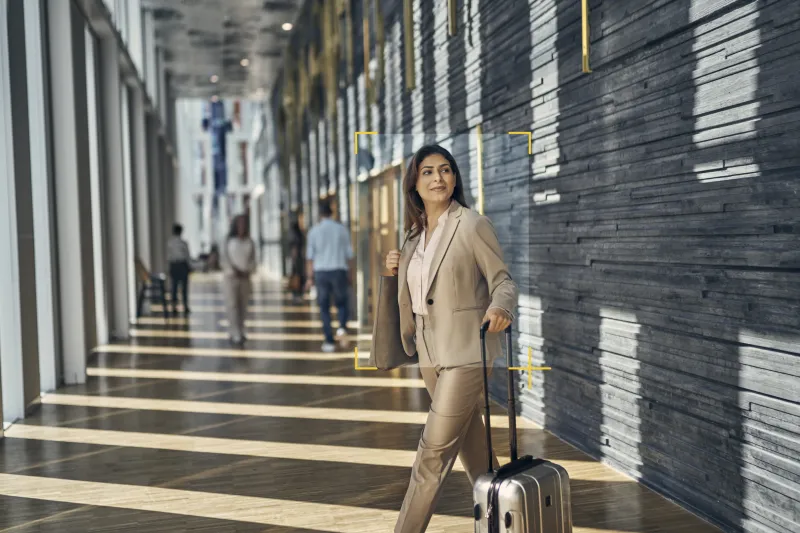 A woman captured on camera with AXIS Analytics walking in a airport with her luggage in hand.