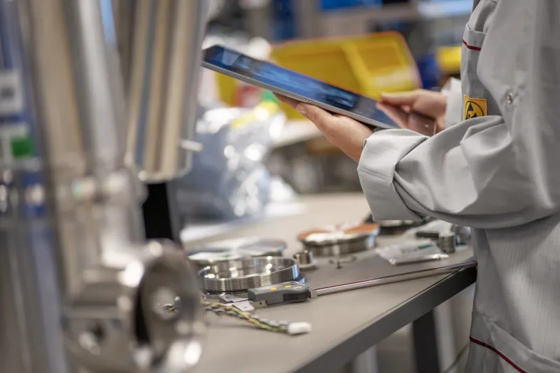 Close up of a worker holding a tablet in an assembly line.