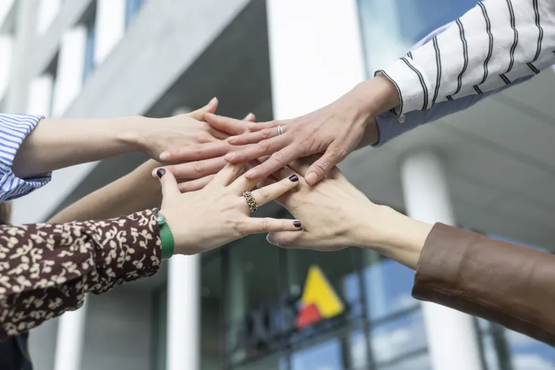 group hands pile outside office