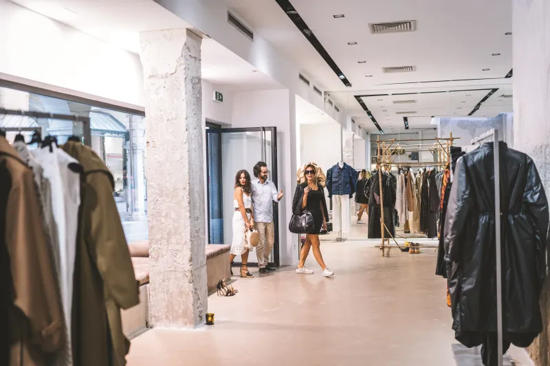 Three people entering a high-end clothing store. 