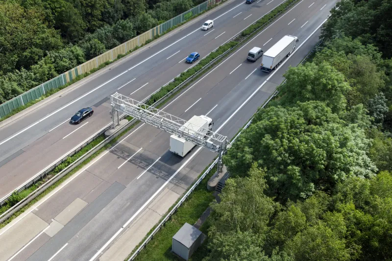 Aerial view of a highway with low traffic surrounded by trees.