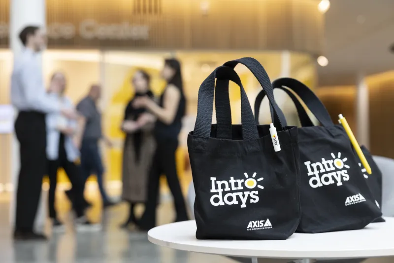 Axis Intro days goodie bags in the foreground. In the background, axis colleague standing outside Axis Experience Center. 