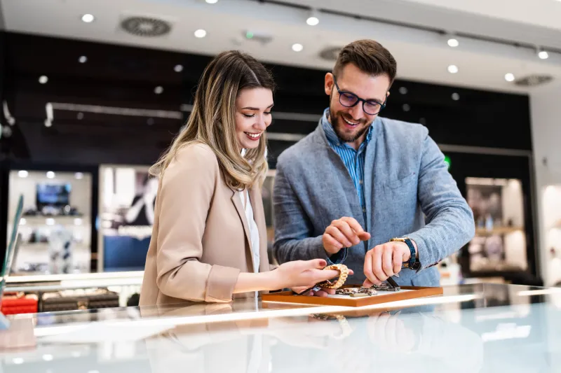 A man and a woman looking at watches over the counter in a luxurious jewelry store.
