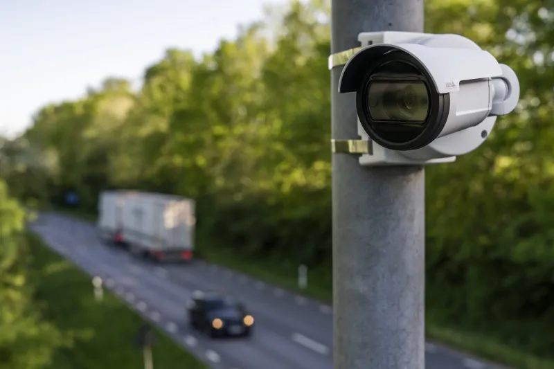 "A white P1486-le bullet security camera is mounted on a metal pole