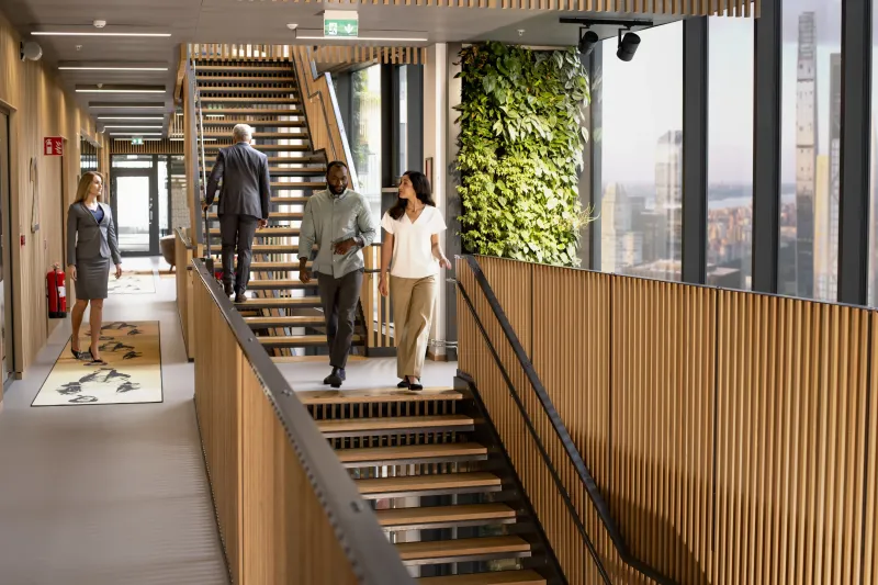 People walking and standing around a large office staircase.