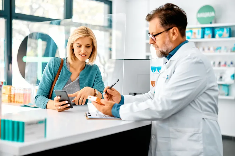 Female customer getting help from a male pharmacist at the counter. 