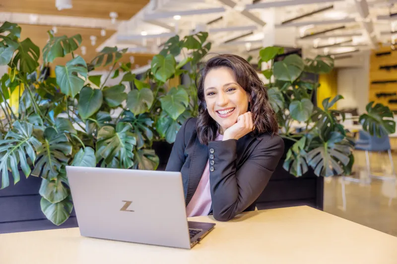 Priscilla, Solutions Development Specialist at Axis, sitting in front of her laptop, smiling.