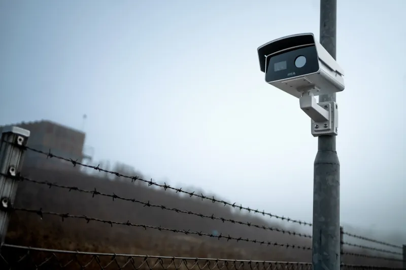 AXIS Q2802-E Bispectral Camera mounted on pole in front of a fence 