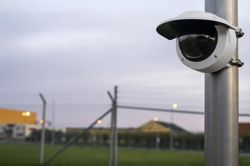 AXIS Q3546-LVE with a weathershield mounted on a pole inside a fenced area.