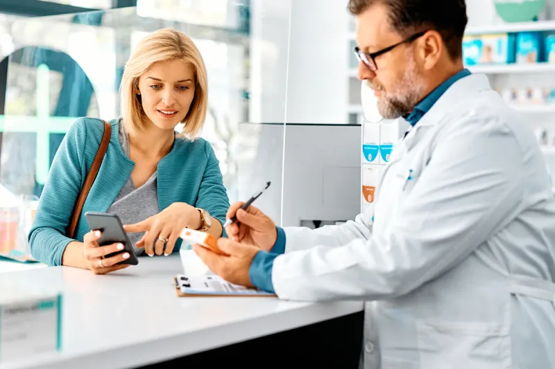 Female customer getting help from a male pharmacist at the counter. 