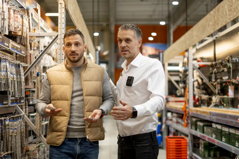 Manager with an Axis body worn camera helping a customer for retail loss prevention.
