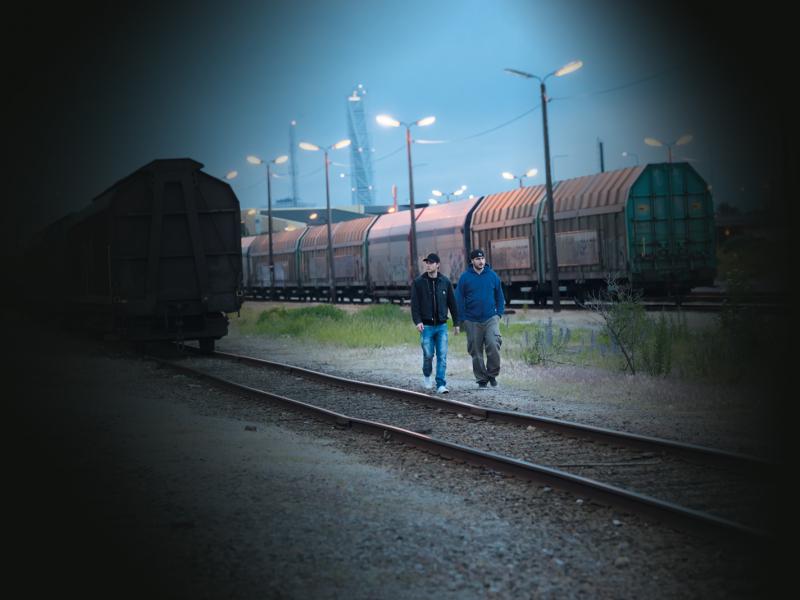 Two men walking on a train track in the dusk