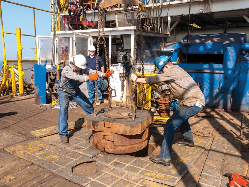 Oil rig workers drilling a hole