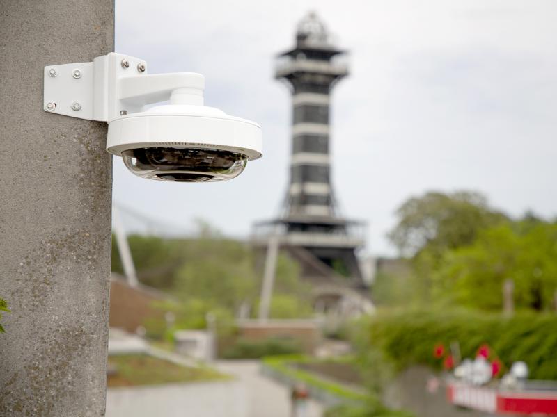 Axis IP camera in daylight at outdoor zoo, mounted to stone wall.
