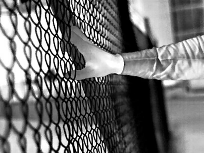 Black and white footage of hand grabbing fence in the dark.