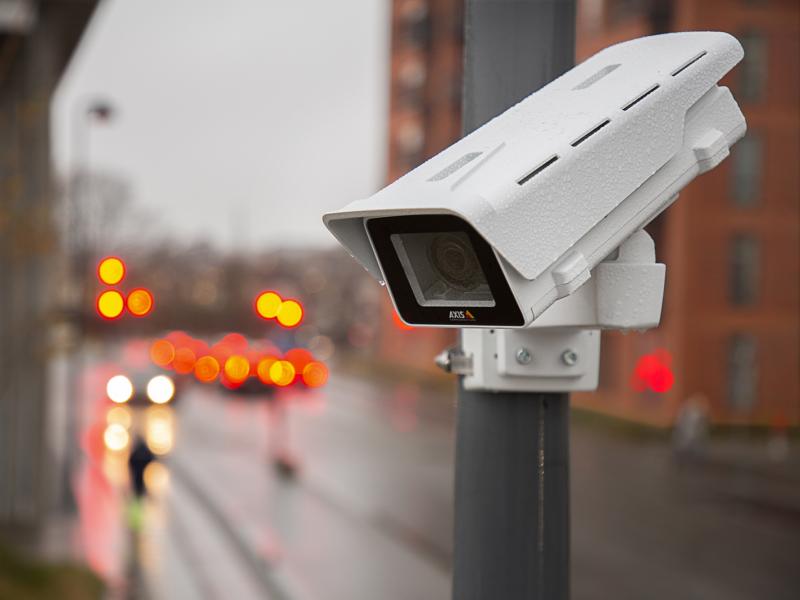 Network camera mounted on a pole in an outdoor environment. Traffic light can be viewed in the background.