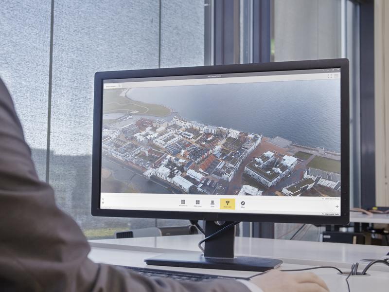 Overview of AXIS Camera Station from a desktop screen, a man sits  by the screen