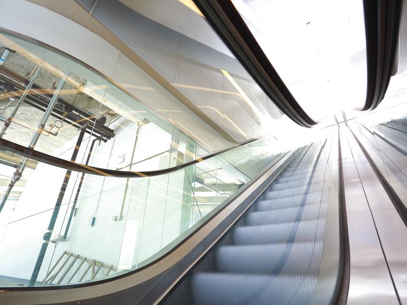 A moving escalator with the sun shining at the top