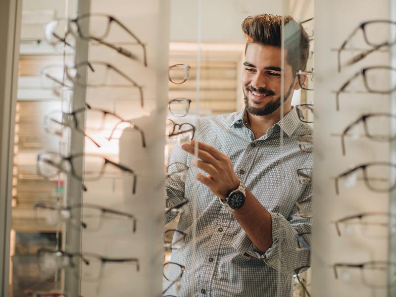 Man in an optician, trying on glasses