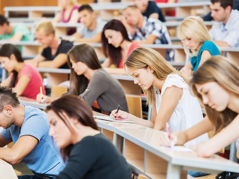 Students sitting in a classroom , writing at their desks