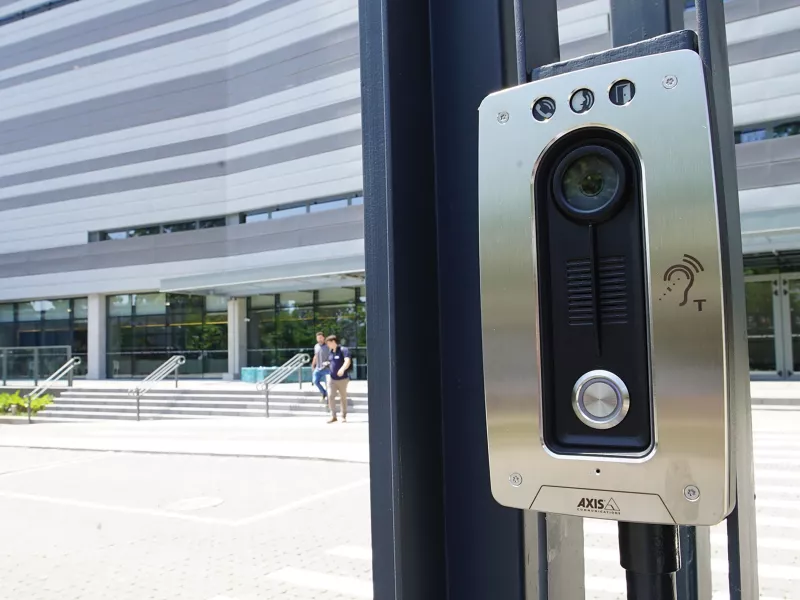 Axis A8004-VE on glass door with two people in the background.