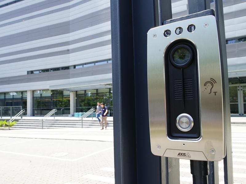 Axis A8004-VE on glass door with two people in the background.
