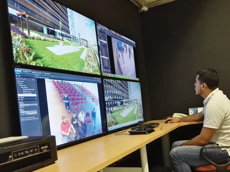 Man viewing four monitor screens.
