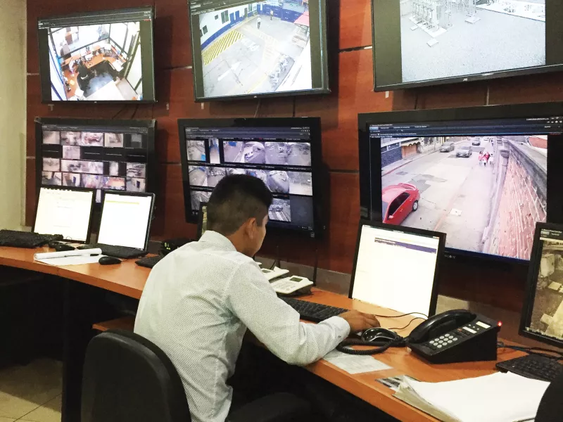 Man in front of a computer screen with several monitors around.