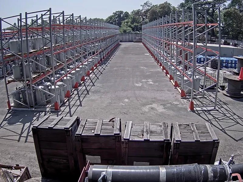 Yard with electric racks placed in a row, trees in far background.