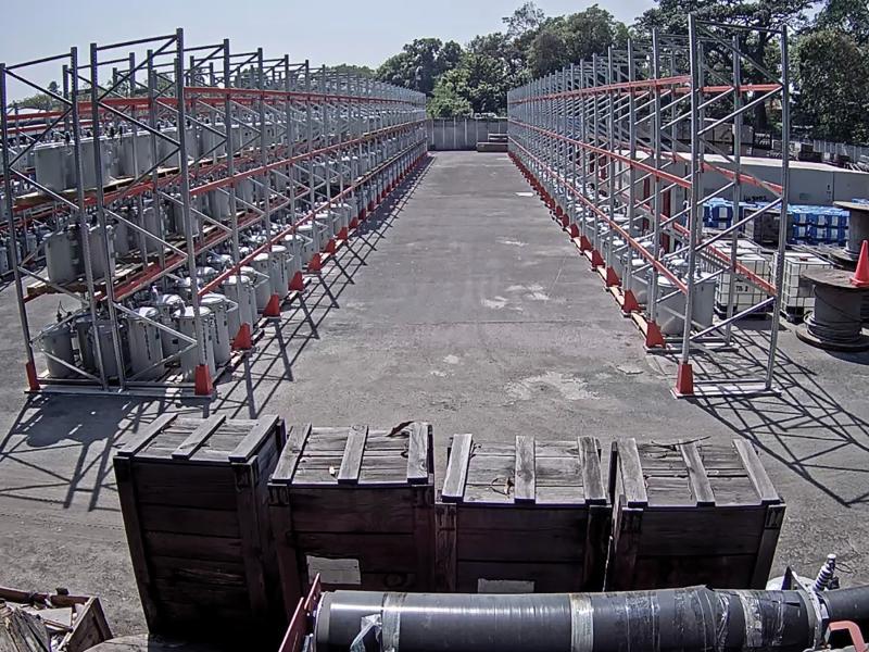 Yard with electric racks placed in a row, trees in far background.
