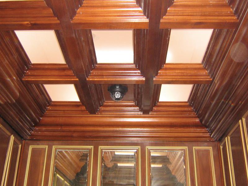 Axis camera in brown ceiling with white squares.