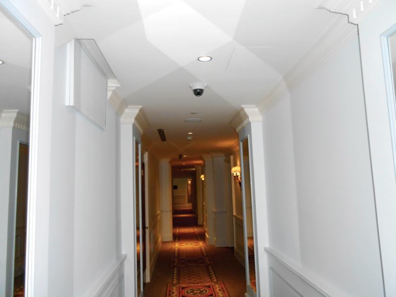 Axis camera in corridor with white walls, yellow lighting at far end.