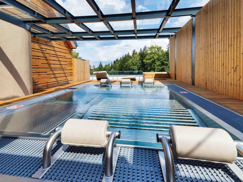 Hotel pool with two wooden walls and glass roof.