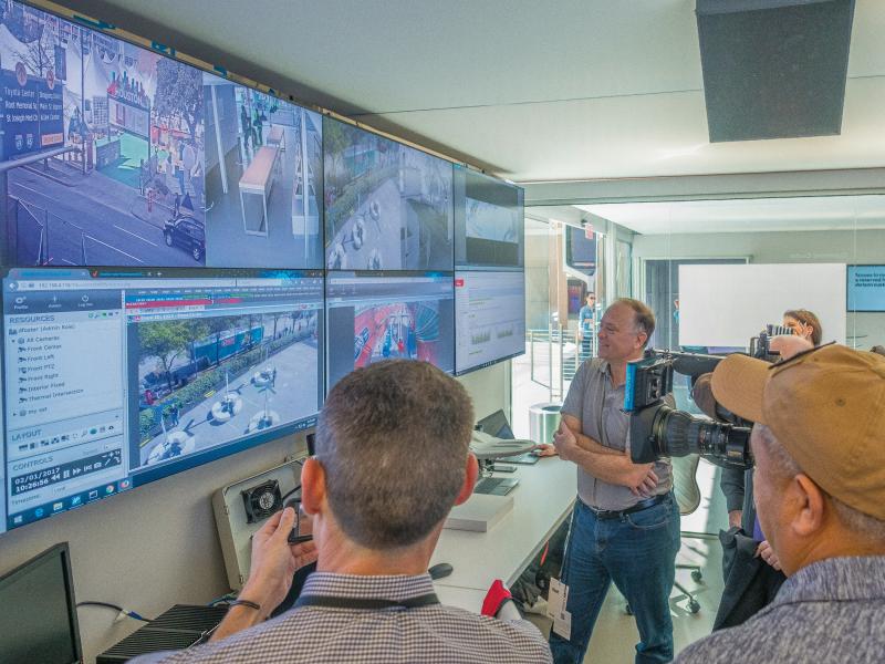 Several men standing in front of multiple monitor screen of superbowl.