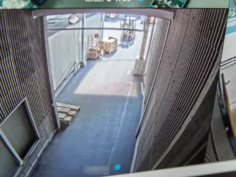 Camera view of warehouse interior entrance, small truck in background.