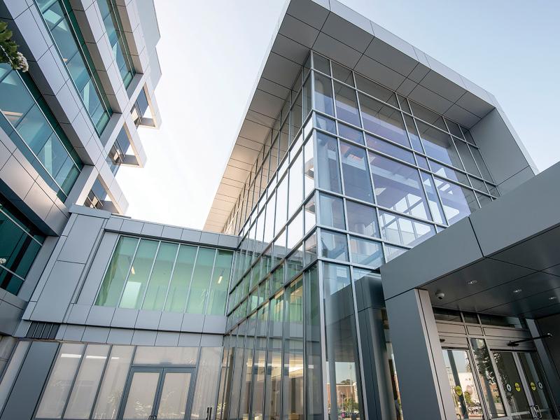 Glass building with parts in different heights, viewed from below.