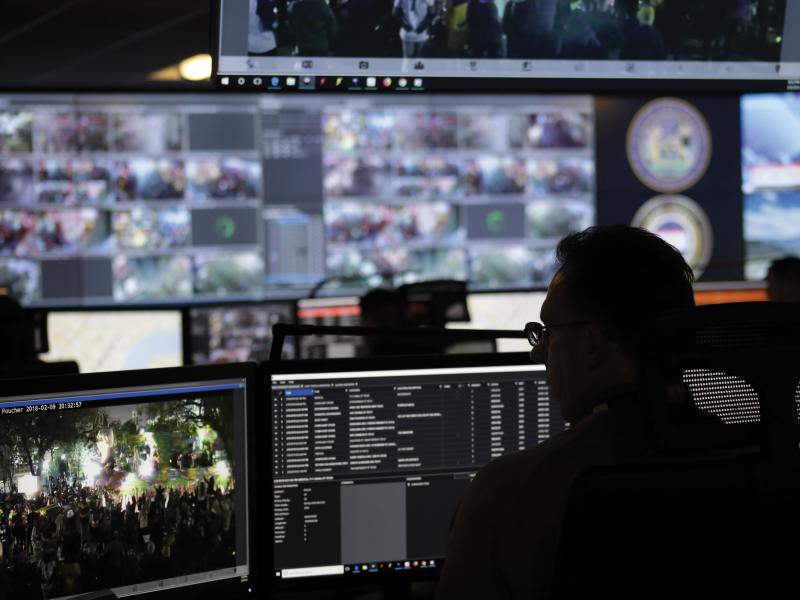 Man viewed from behind in dark monitor room.