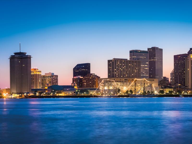 New Orleans skyline in evening, a few skyscrapers with blue water and sky.