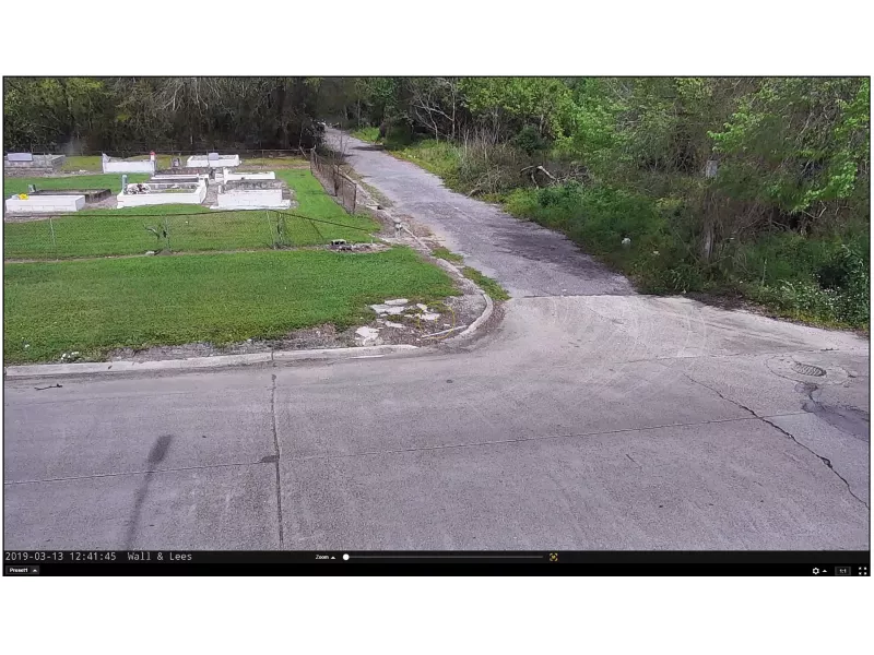 Screenshot of road turn, grass and small white buildings.
