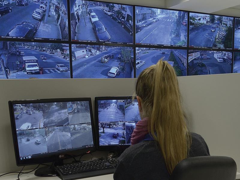 Woman viewing multiple monitor screens showing streets.