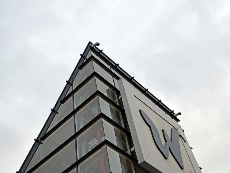 Axis camera on top of Waasland's grey building, viewed from below.