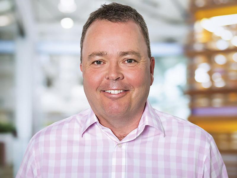 Man in pink and white shirt smiling to camera.