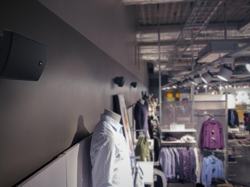 AXIS C1004 speaker mounted on the wall of a clothingstore