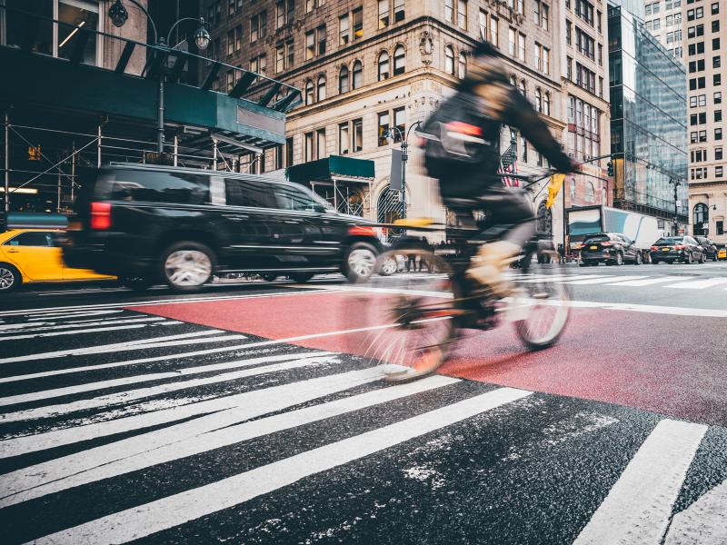 Blurry picture of a street with a car and bicycle passing by